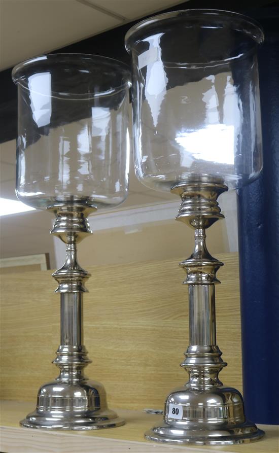 A pair of glass storm lamps, on plated bases